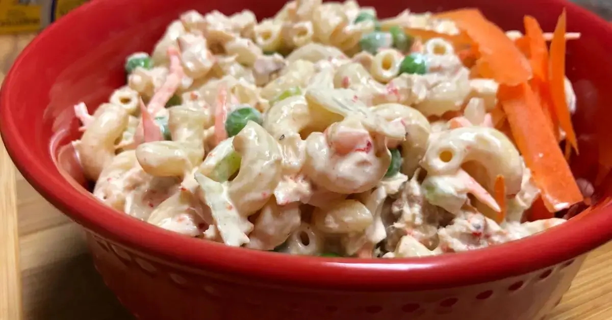 tuna pasta salad in red bowl with carrot slivers as garnish