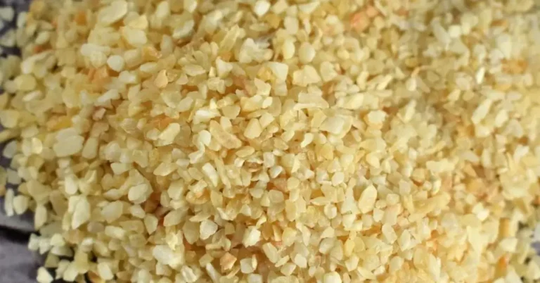 A small pile of garlic powder on a gray background.