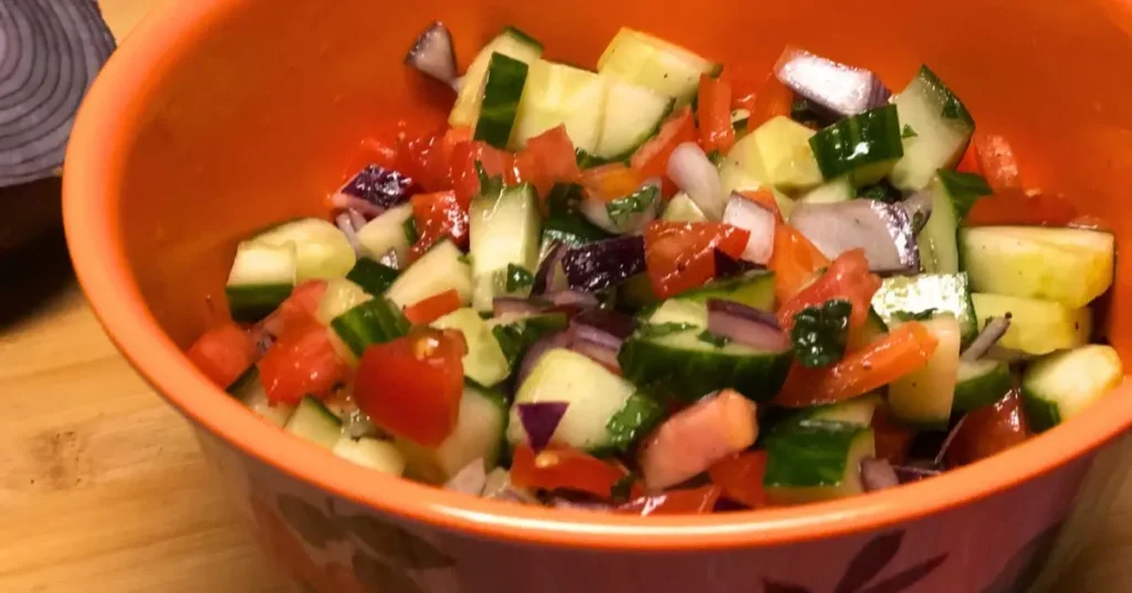 Fresh Israeli salad in a small flowered bowl, fully mixed and ready to serve.