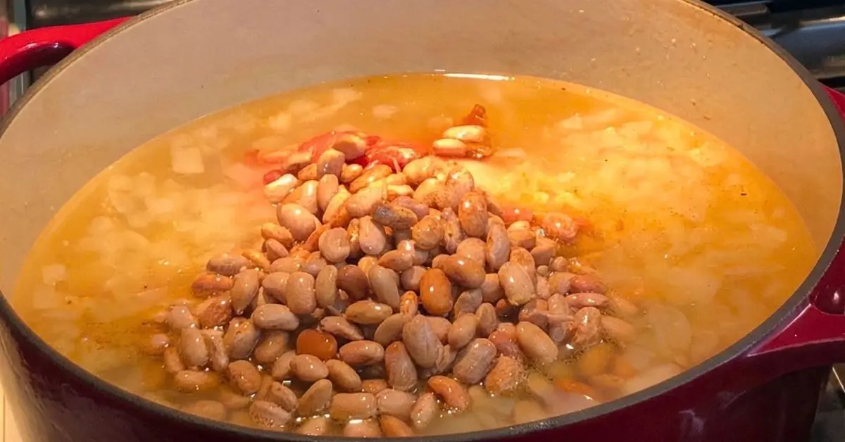 Smoked turkey wing simmering in a broth-filled Dutch oven on the stove.