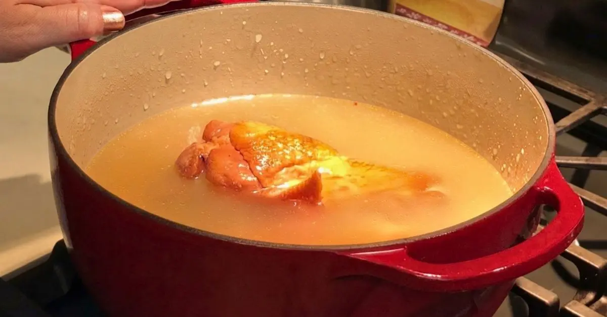 Raw pinto beans poured into a Dutch oven with broth and onions for cooking.
