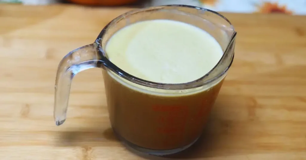 chilled chicken broth in measuring cup with a layer of fat on top.