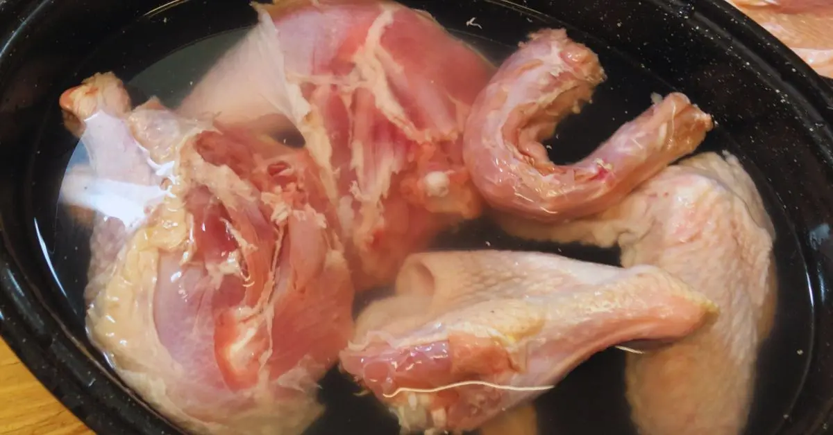 Turkey pieces that have been cut from a whole turkey in cold water soaking.