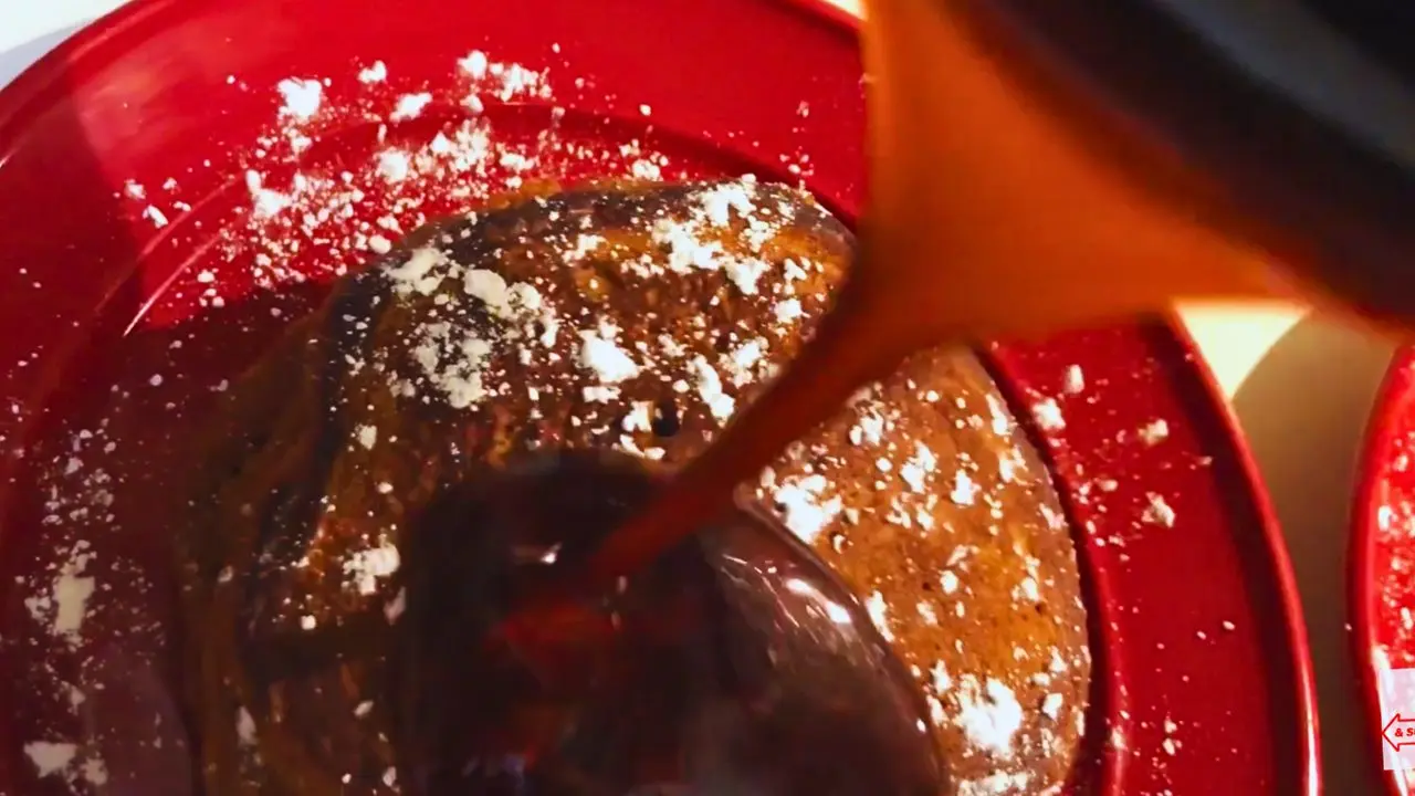 Top view of gingerbread pancakes with molasses syrup being poured over the stack.