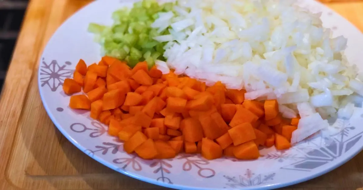 chopped and diced stew vegetables, like carrots, onions and celery on a snowflake plate.