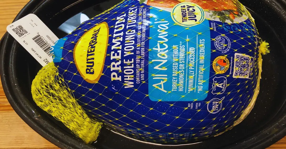 butterball turkey in packaging in large black roaster, thawing out.
