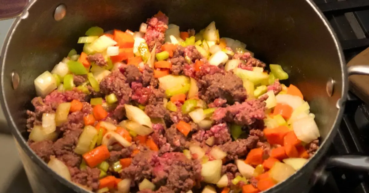 Ground beef browning and vegetables sautéing together in a pot for Shoney’s cabbage soup.