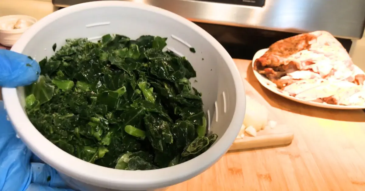 frozen collards in a white bowl being shown in front of a plate of smoked turkey and stove