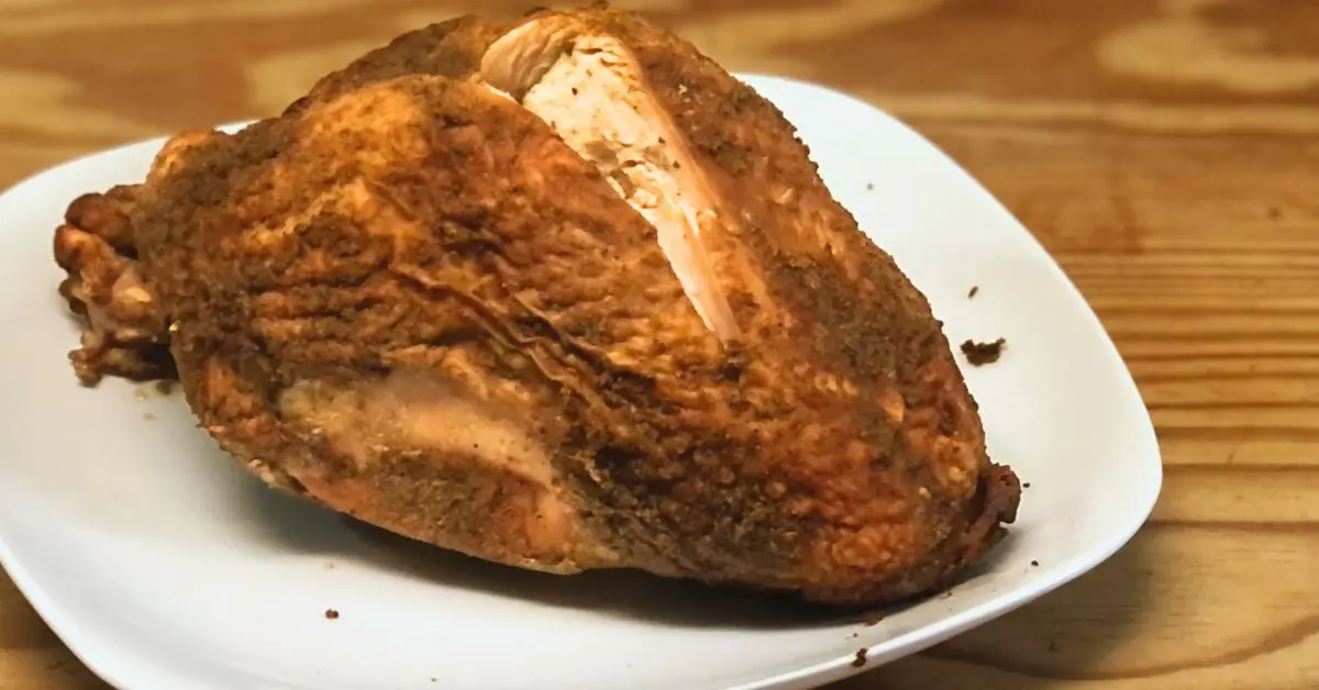 whole smoked turkey breast on white plate on table