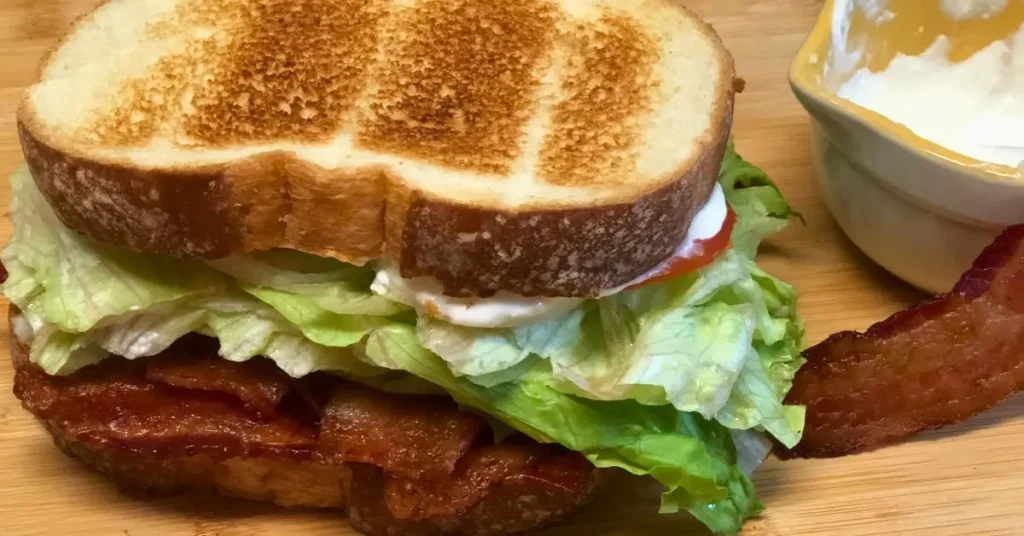 Bacon BLT sandwich stacked high with lettuce and tomato served with horseradish mayo sauce