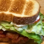 Bacon BLT sandwich stacked high with lettuce and tomato served with horseradish mayo sauce