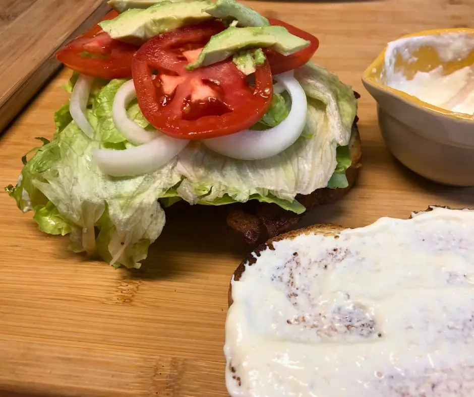 Building a Bacon BLT sandwich with layered vegetables and horseradish mayo