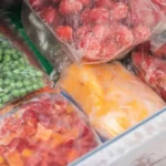 Frozen vegetables in storage bags stacked in the bottom freezer door