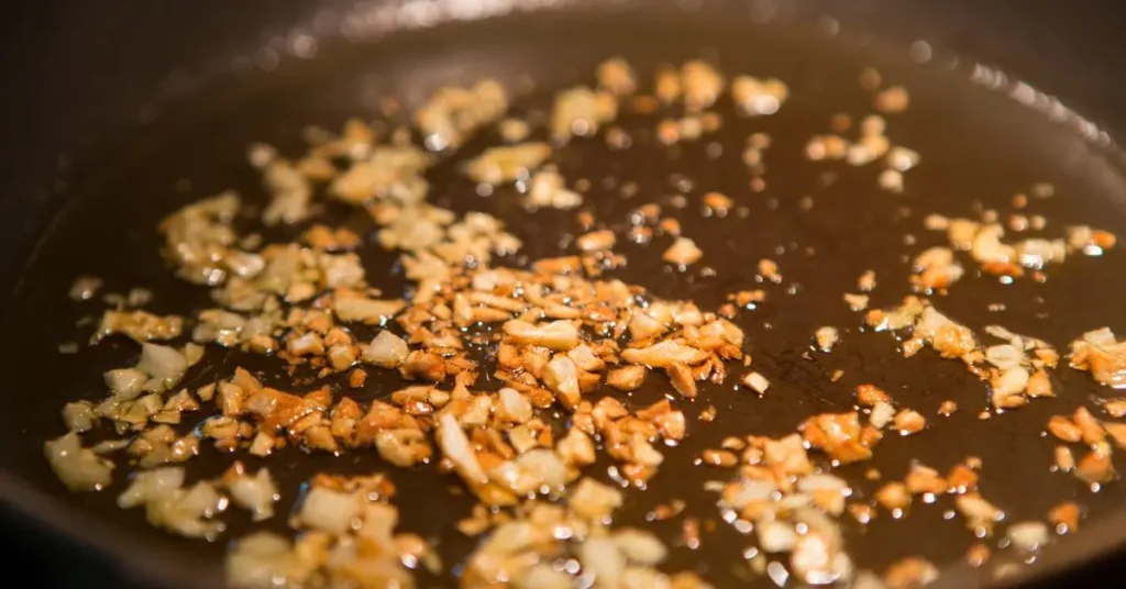 Minced garlic browning in a black skillet with oil