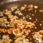Minced garlic browning in a black skillet with oil