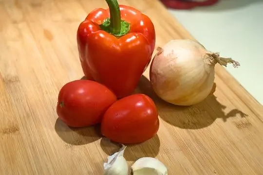 Red bell pepper, sweet onion, roma tomatoes, and garlic cloves for country succotash recipe