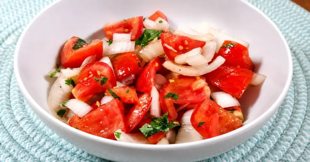 Fresh tomato and onion salad with lemon, herbs, and colorful cherry tomatoes in a serving bowl.