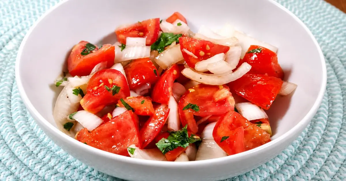 Fresh tomato and onion salad with lemon, herbs, and colorful cherry tomatoes in a serving bowl.
