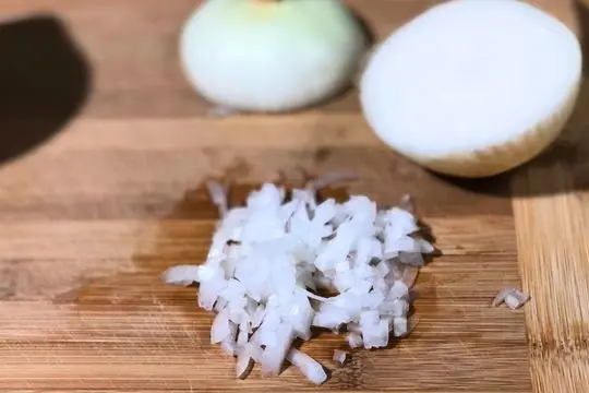 Sweet onion sliced and diced on a cutting board for Southern tomato pudding.