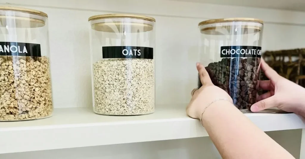 Clear pantry jars filled with oats, chocolate chips and granola