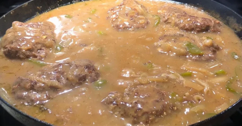 Salisbury steak patties simmering in brown onion and green pepper gravy