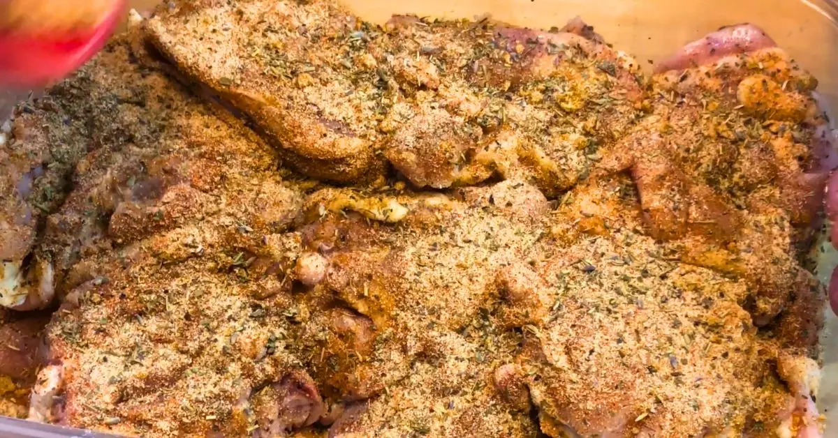 Raw chicken thighs coated with seasoning before baking in the oven.