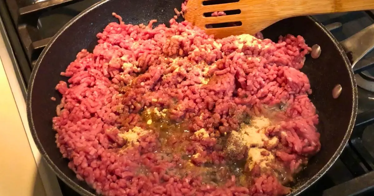 Seasonings sprinkled over ground beef in a skillet