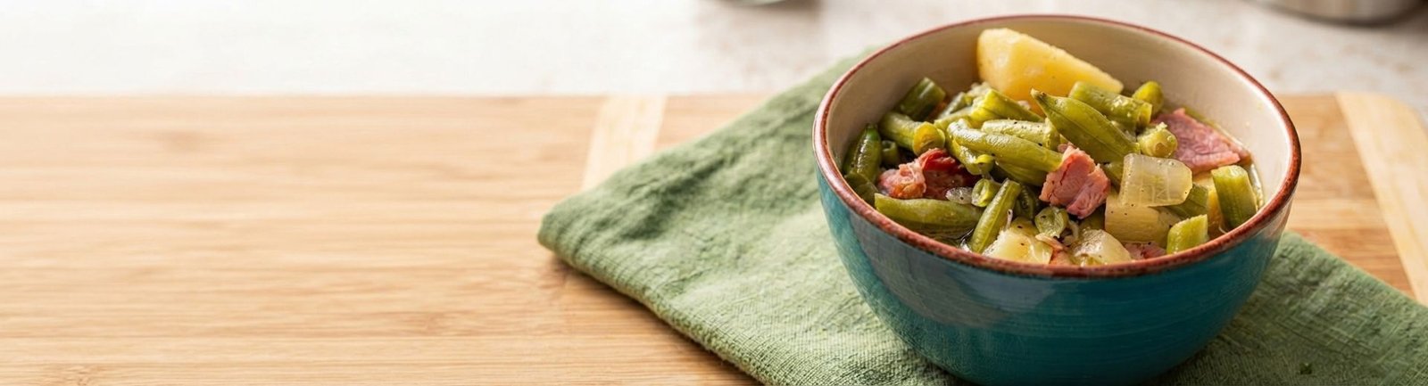 teal bowl filled with green beans, ham and potatoes