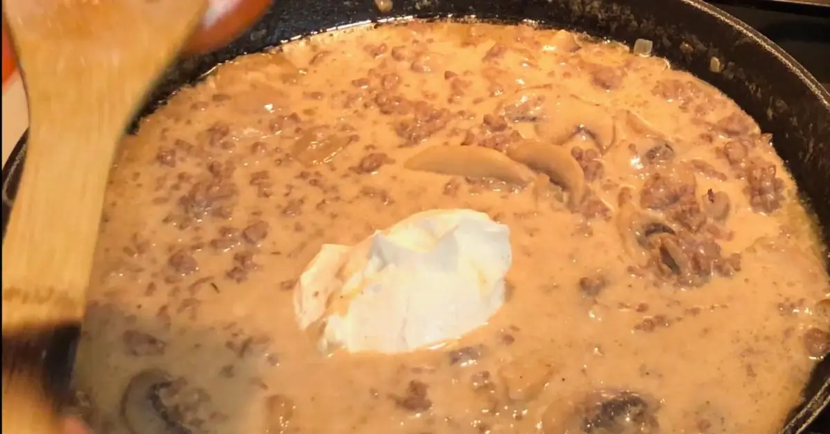 Sour cream being added to the creamy stroganoff sauce