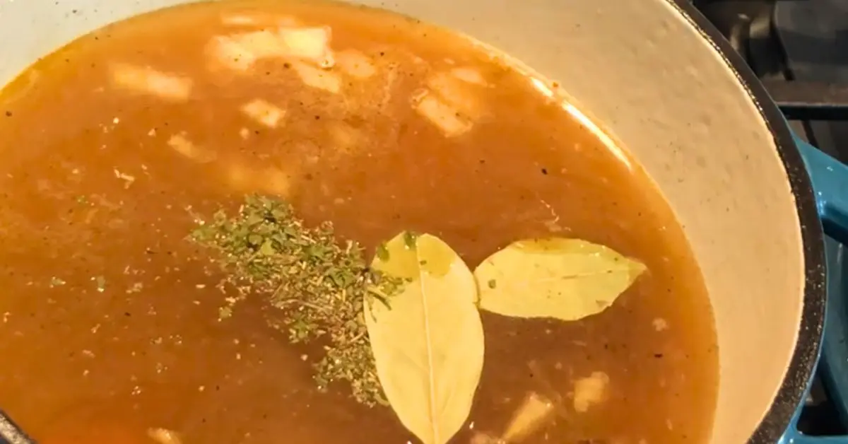 Chicken broth with herbs and bay leaves in a Dutch oven for split pea soup