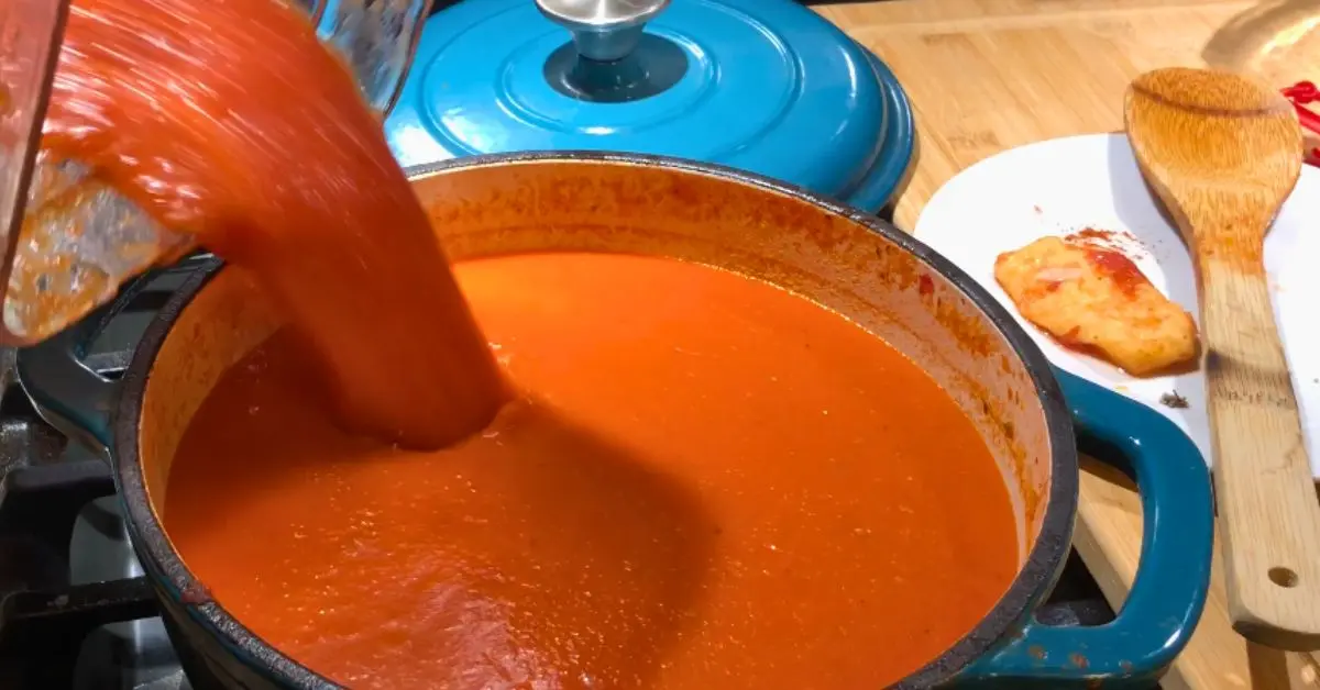 Blended tomato soup being poured from a blender back into the pot