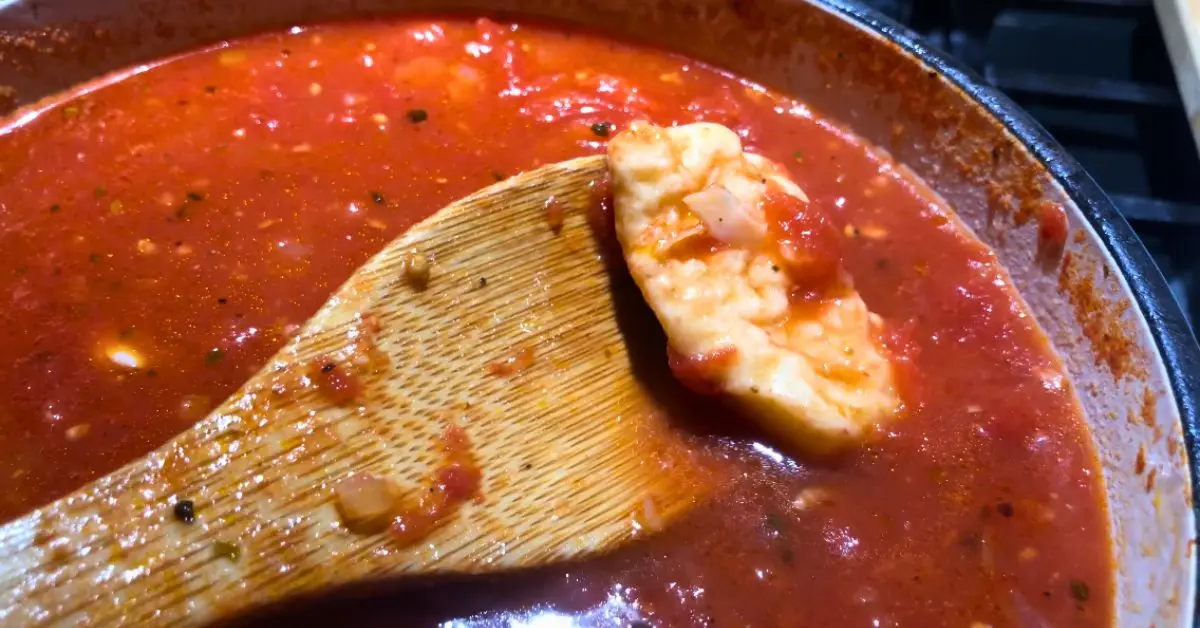 Creamy tomato soup simmering with a Parmesan rind in the pot